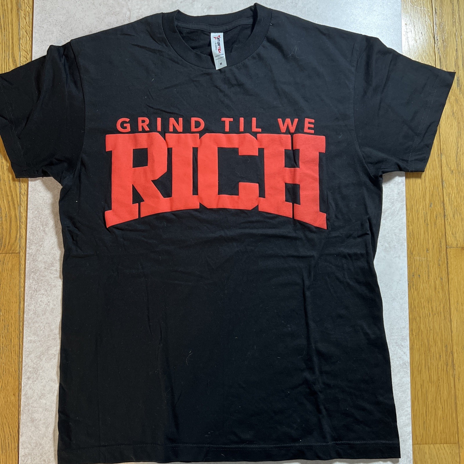 Grind Til We Rich Men’s Med Relaxed Fit Puff Print T Shirt. Melrose Boutique